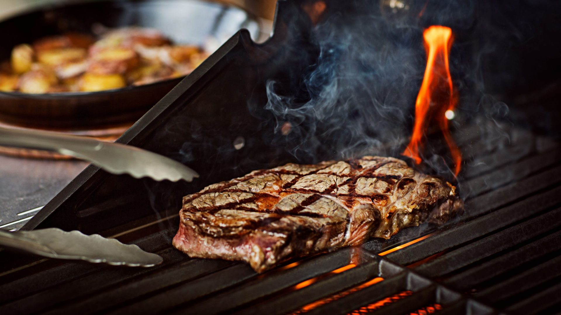 Ein Steak auf einem Grill mit Flammen.