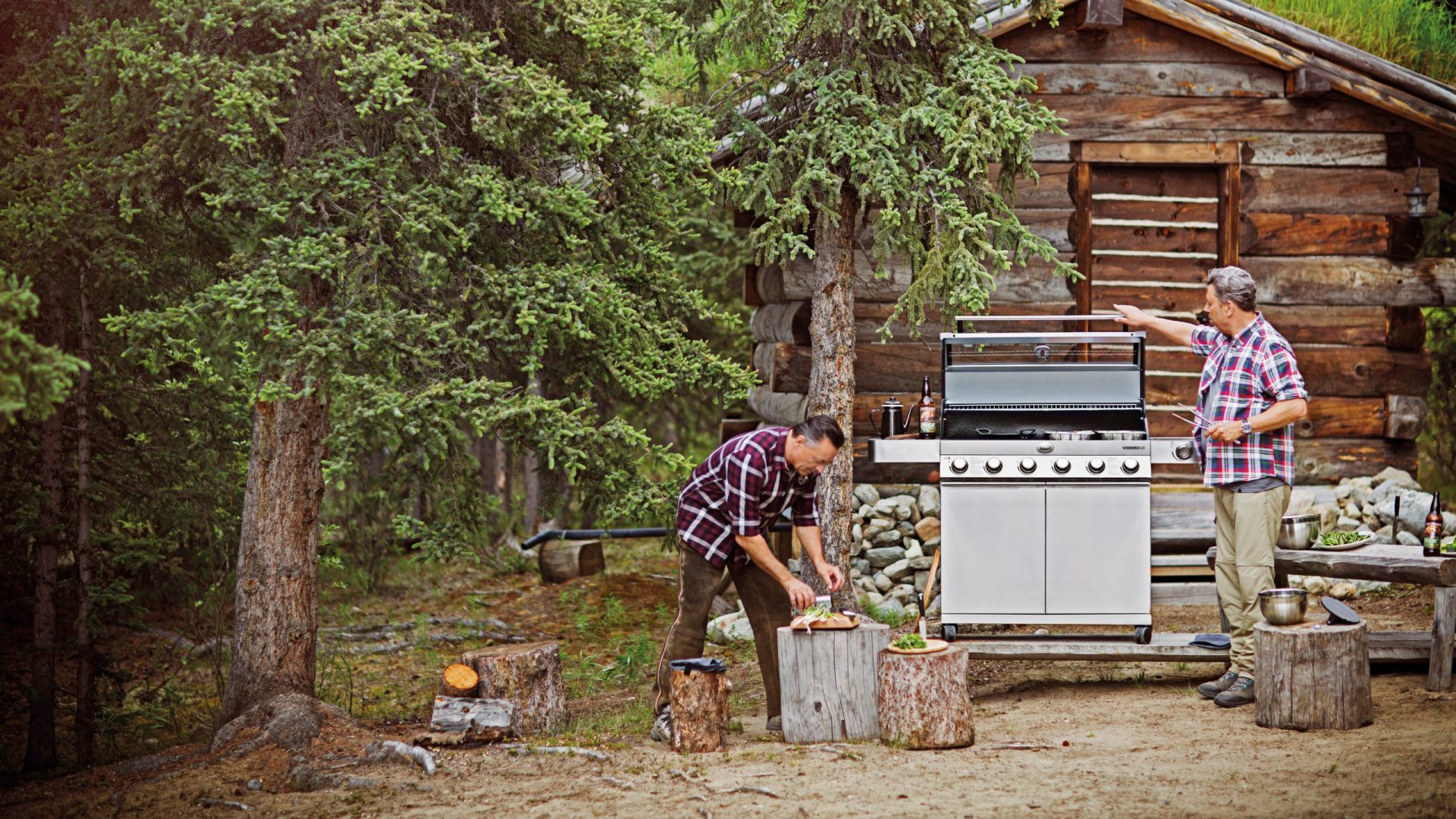Rösle Fotoshooting mit einem Grill vor einer Blockhütte.
